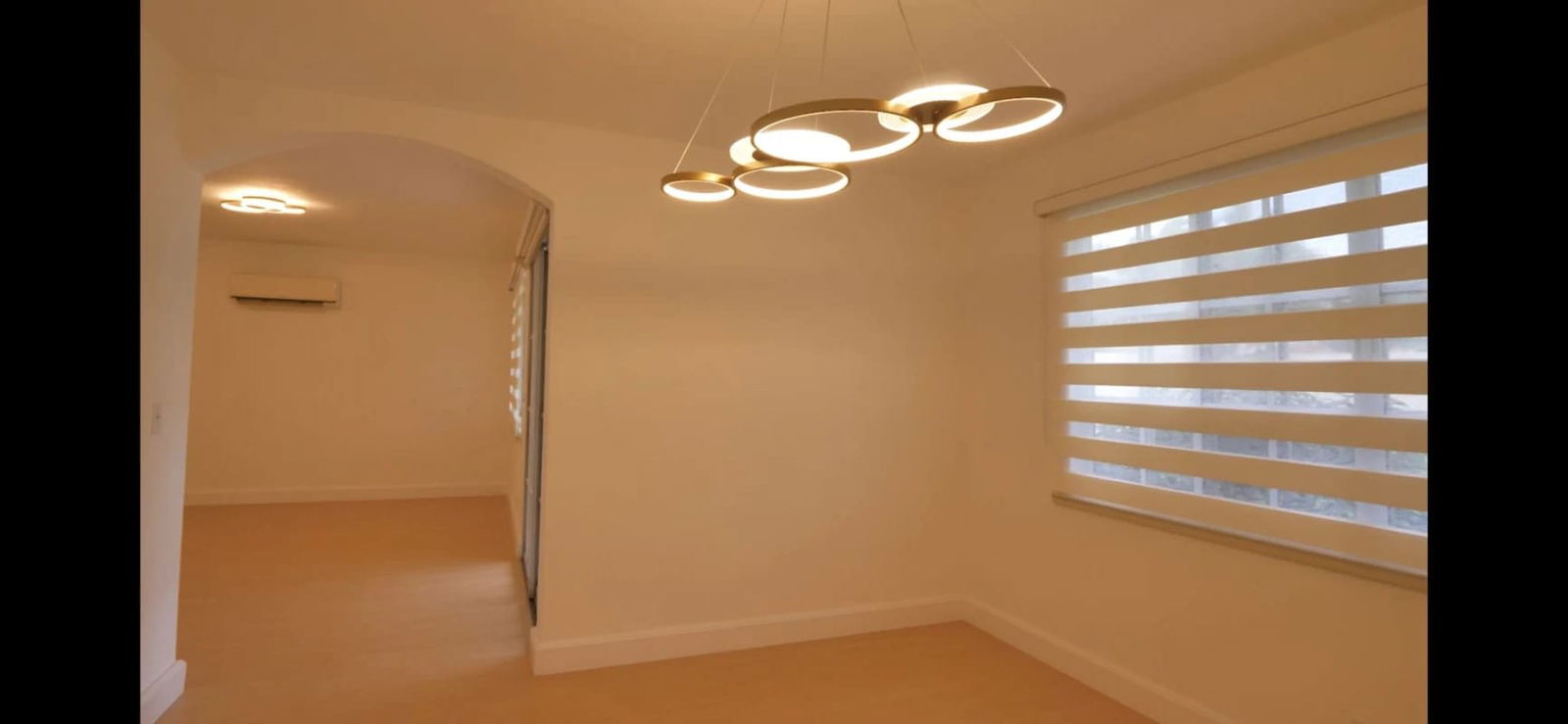 Minimalist dining room with circular lamp, modern blinds, arch doorway in Albrook rental house