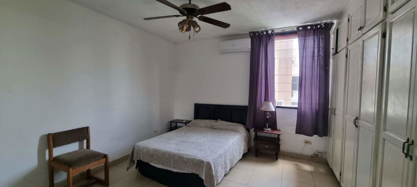 Bedroom with panoramic corner windows city view vanity AC and ceiling fan in PH Park Loft Panama