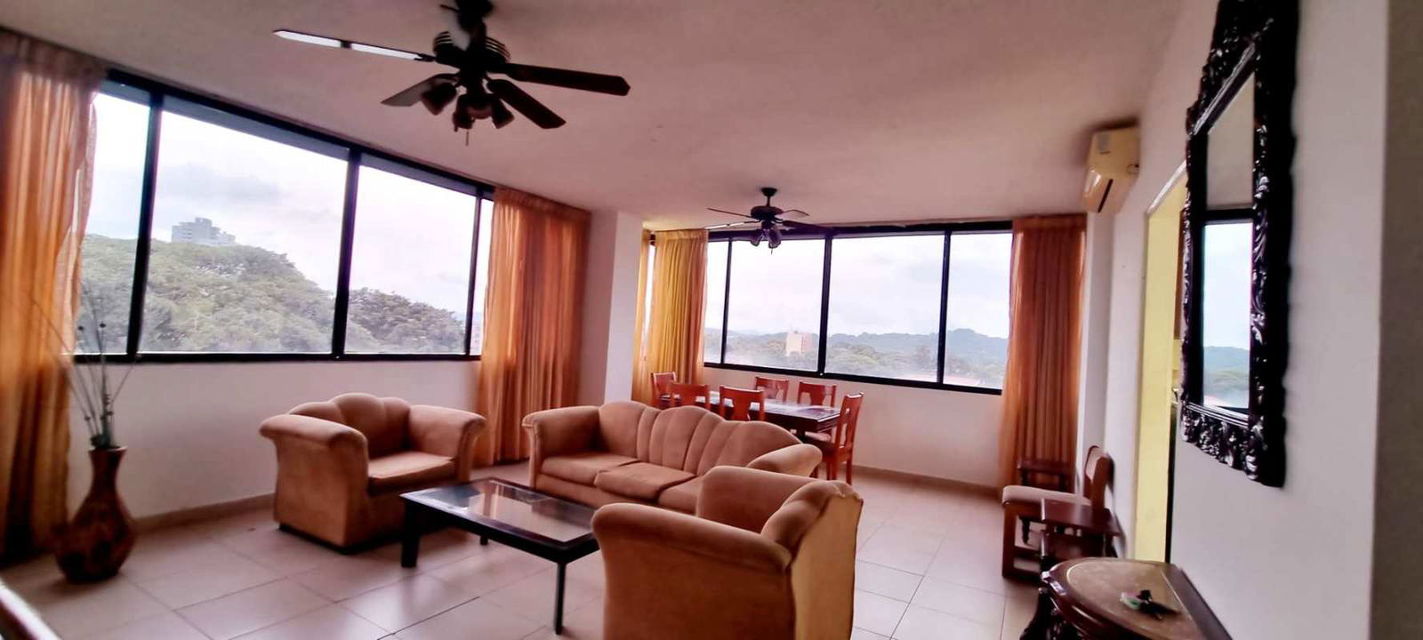 Furnished living area with ceiling fan, beige sofas and panoramic windows in El Cangrejo Panama