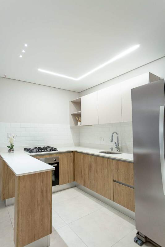 Bedroom with wood panel accent wall, minimalist bed and ceiling lights in Mi Condado Panama City