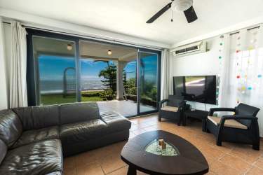 Modern kitchen and living area with tile floors, wooden cabinets, staircase in Malibu Beach compound