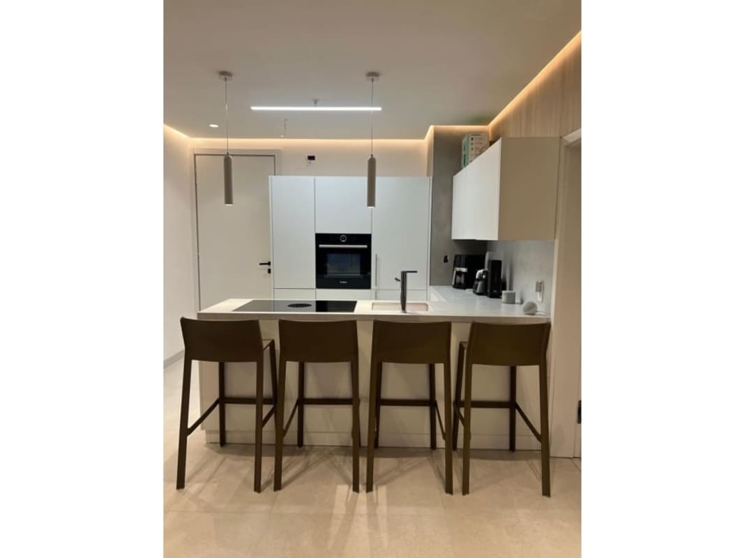 Contemporary kitchen with built-in oven, island and pendant lights in Coco del Mar apartment