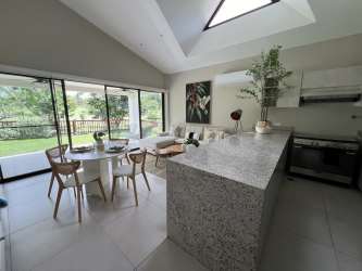 Open modern kitchen with granite island and garden view dining area in Terra Viva Coronado house for sale