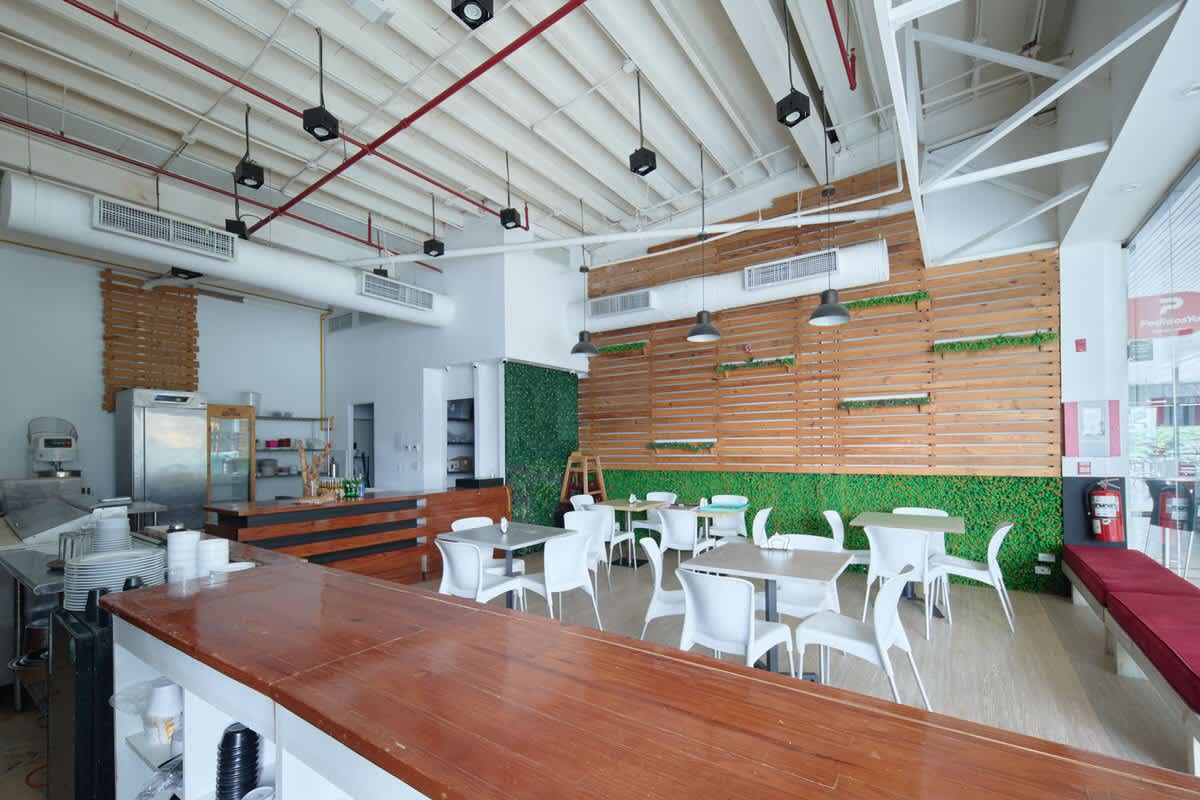 Modern restaurant dining area with exposed ceiling, plants and wooden accents in PH BICSA Panama