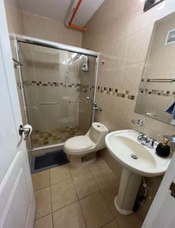 Modern bathroom with glass shower enclosure, beige tiles, pedestal sink PH San Francisco Bay Panama City