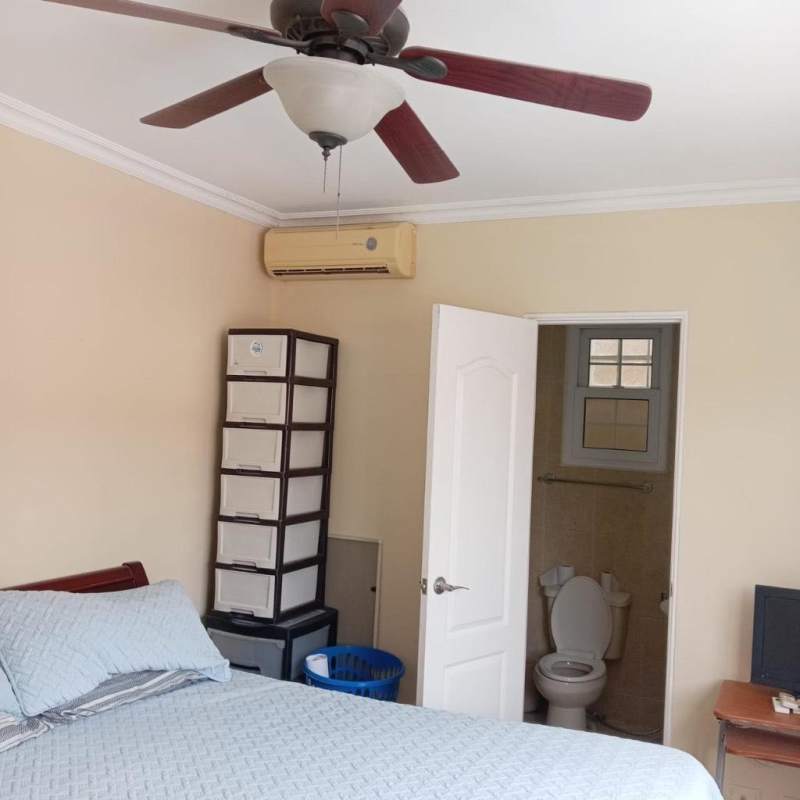 Furnished bedroom with ensuite bathroom, AC, fan, and natural light in Brisas del Golf Panama