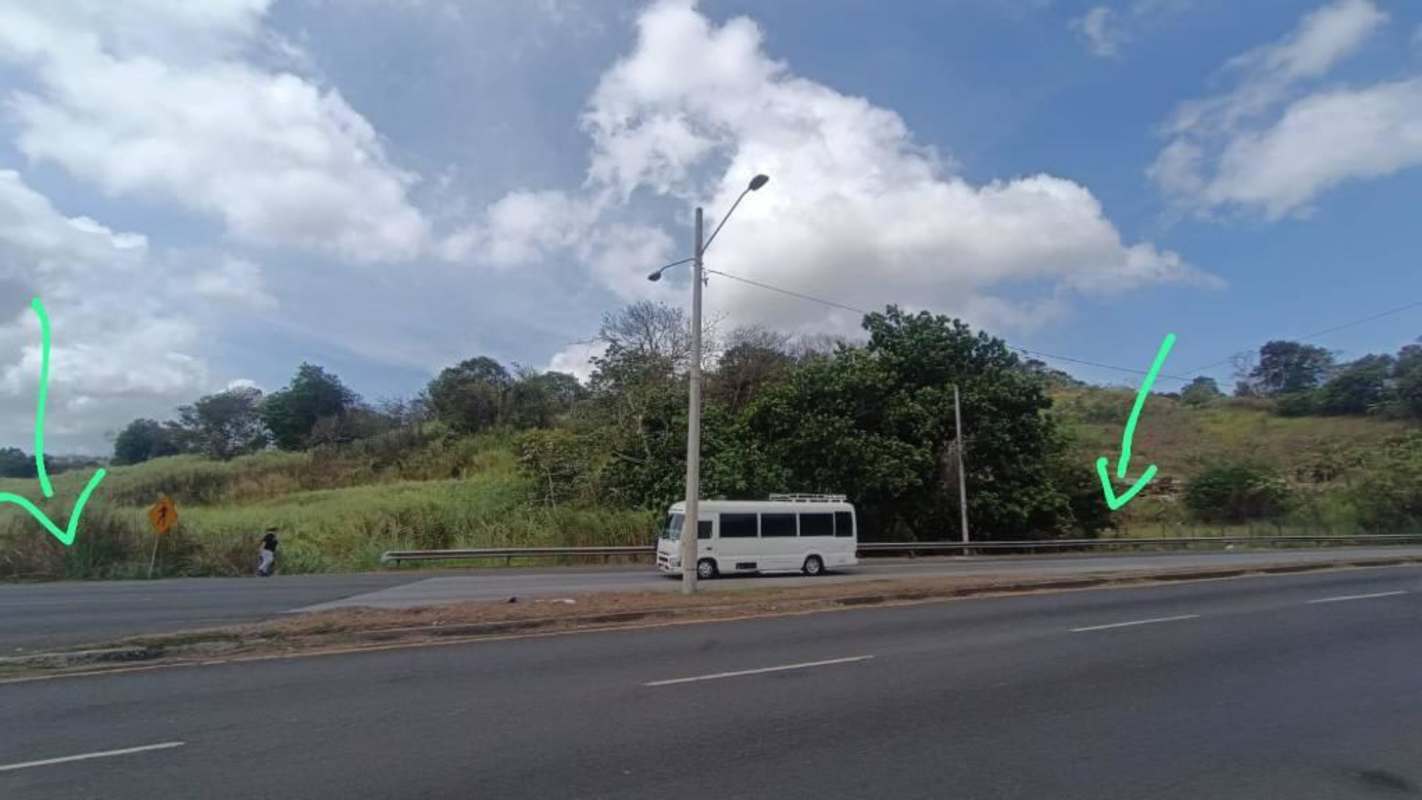 Roadside perspective of large empty parcel along Transistmica avenue at Las Cumbres ready for development in Panama City