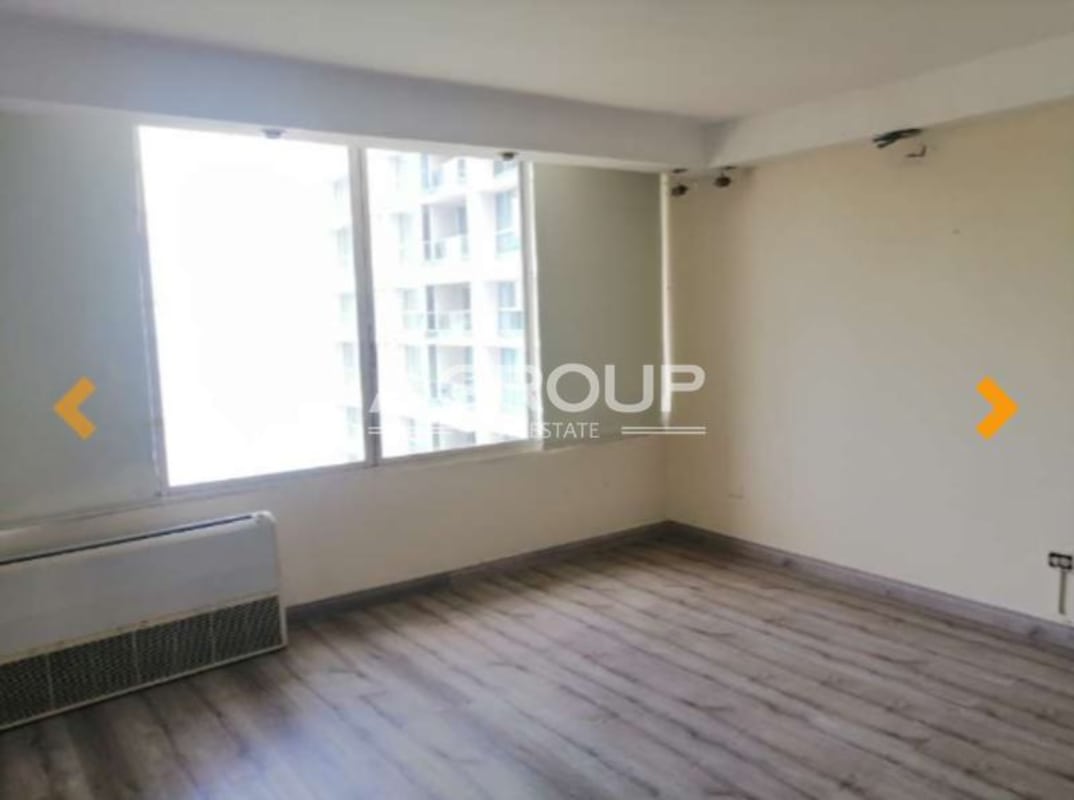 Bright living space with large windows, wood flooring, and AC unit at Torres del Pacífico Panama City