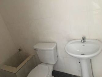 Minimalist bathroom with pedestal sink, toilet and utility sink inside commercial rental unit at Plaza LG Arraiján