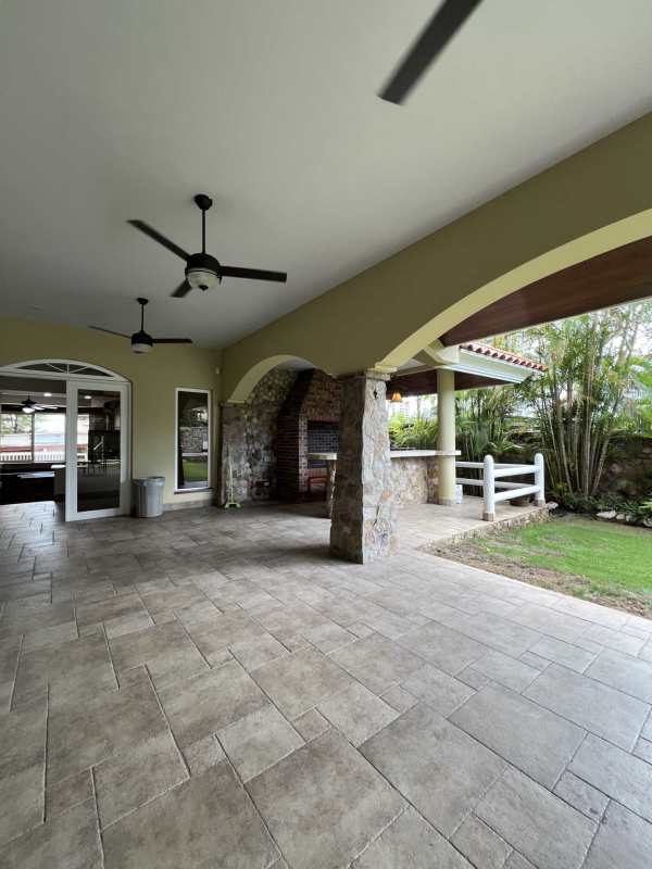 Rustic covered patio with brick BBQ, wooden ceiling fans, garden in luxury house Altos del Golf Panama City