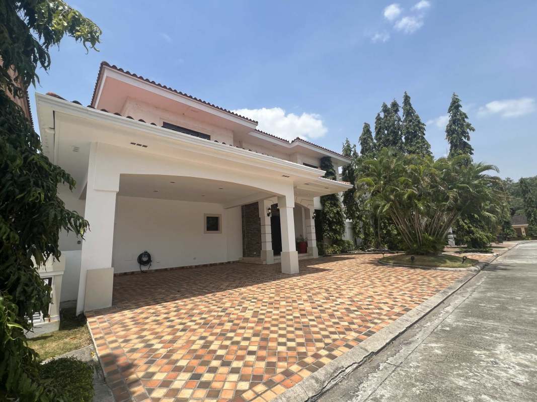 Elegant two-story house with red tiled roof, landscaped garden and covered carport in Costa del Este Panama