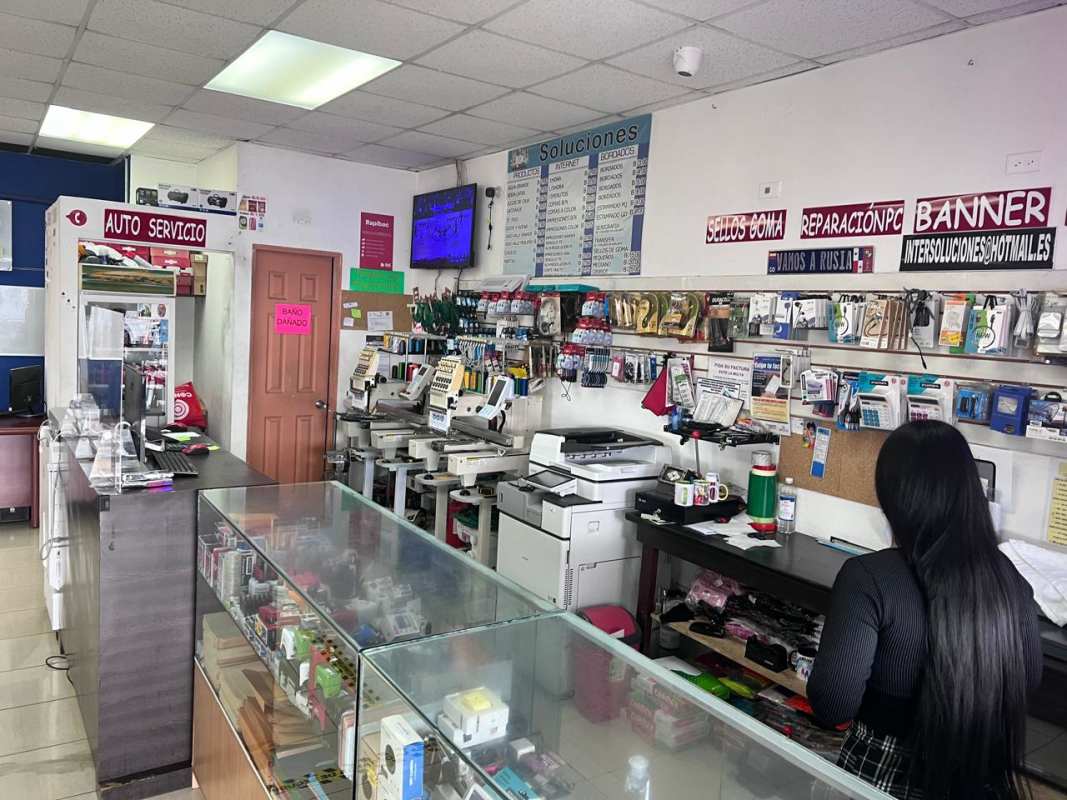 Interior of copy print shop with counters, printing equipment, signage in San Miguelito Panama