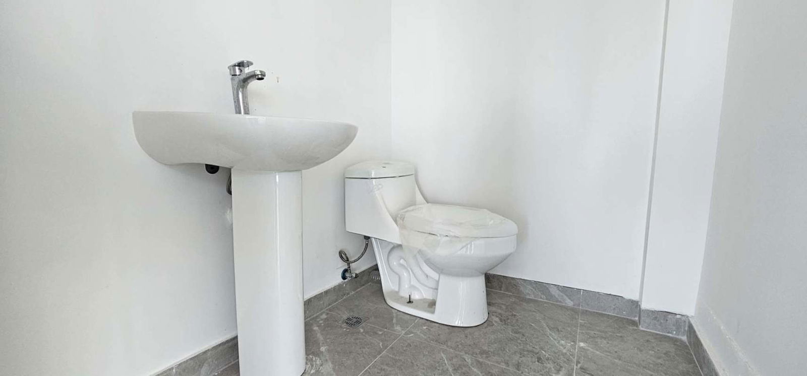 White minimalist bathroom with sink and toilet, gray tile within Sortis Business Tower Obarrio office rental