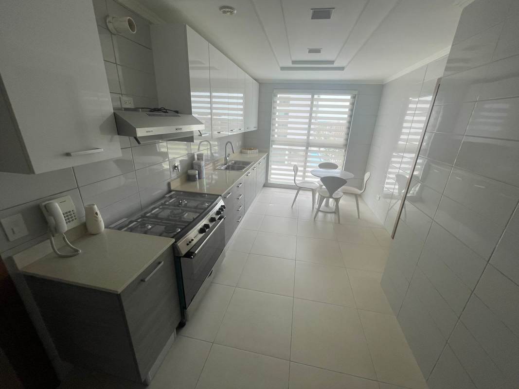Minimalist white kitchen with built-in appliances and small dining set in PH Park Lane Costa del Este
