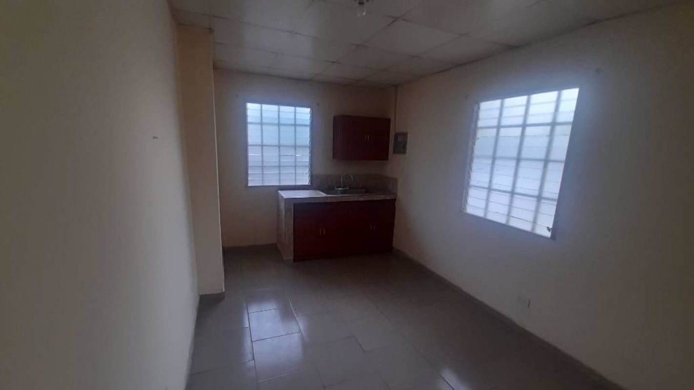 Minimalist kitchen with tiled floor barred windows and wooden cabinets Ciudad Radial rental Panama