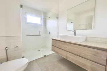 Contemporary bathroom featuring glass shower, floating wood vanity at Playa Venao Residences
