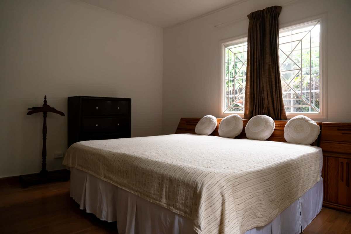 Bedroom with large window, dark wood furniture, natural light in house Obarrio Panama
