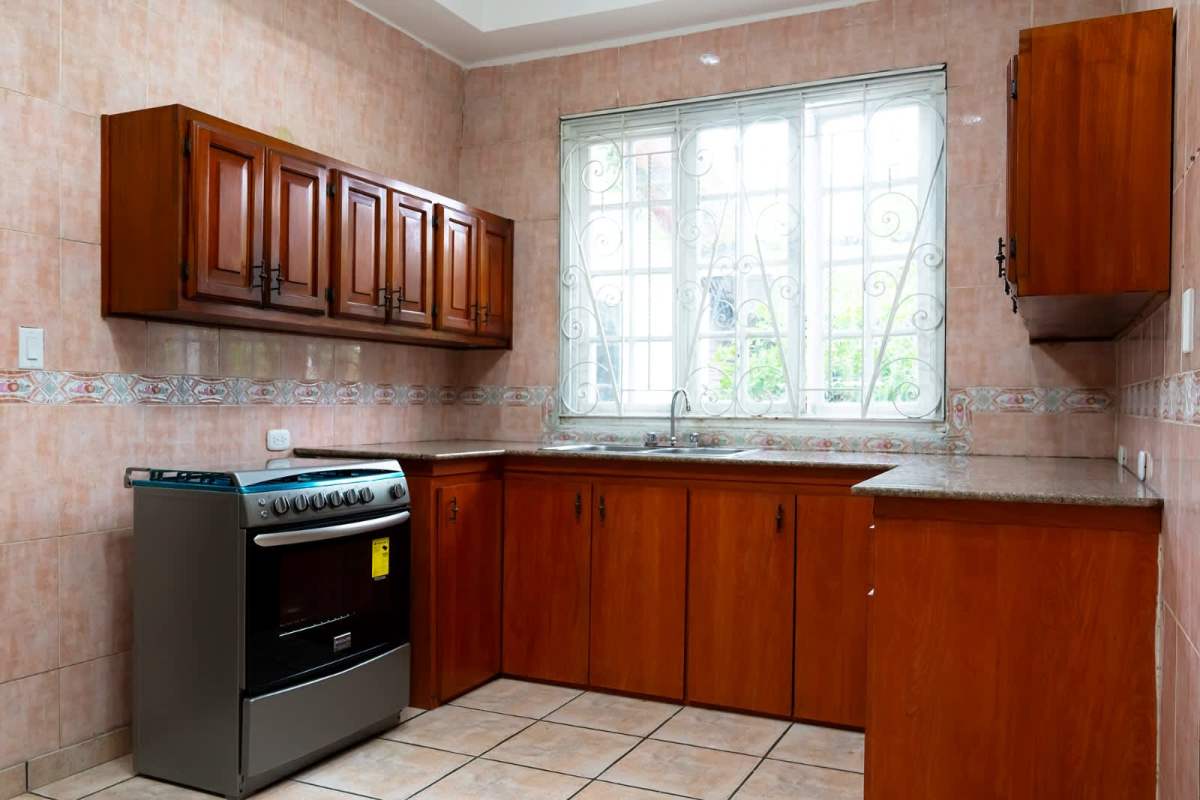 Large kitchen with wood cabinets granite countertops window in Obarrio house Panama