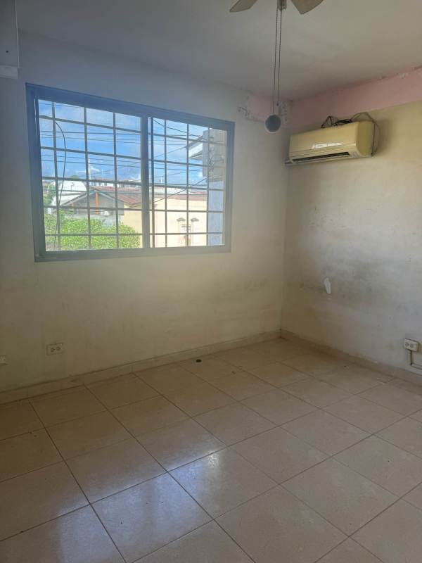 Bedroom with ceramic floor, AC unit, and metal-barred window at PH Las Quintas Panama