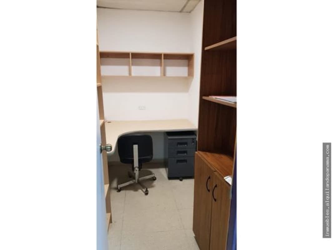 Private office with wood panel walls L-shaped desk blue chair shelves at Altos del Chase Business Center Betania Panama