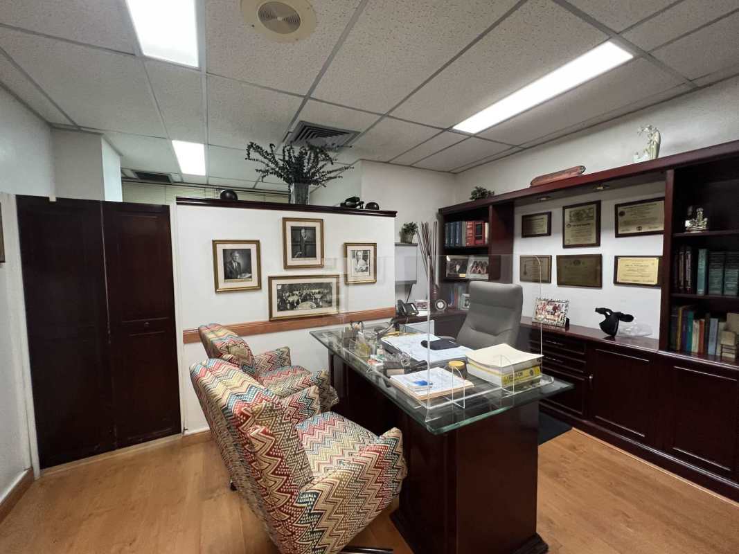 Interior of professional private doctor's office with glass desk, cabinetry, artwork within Consultorios Médicos Paitilla