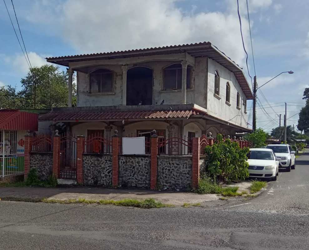 Two-story detached house with balcony, arched windows, iron fence on city street La Chorrera