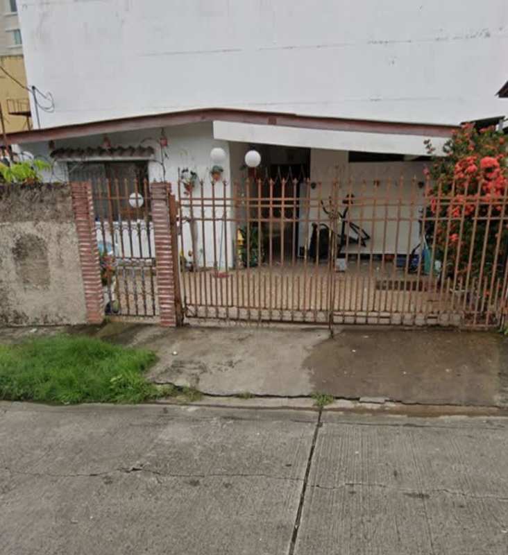 Modest residential house with brick gate pillars, metal fence and shrubbery Panama City