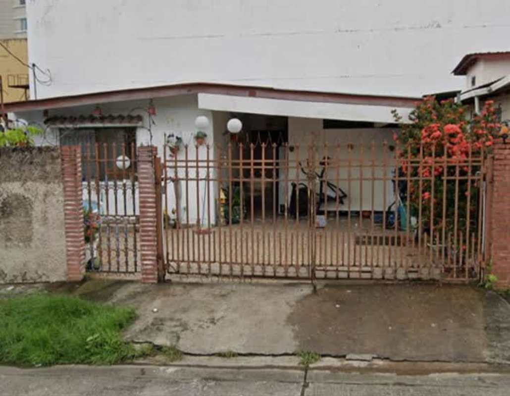 White-walled house with brown metal fence, porch, garden plants in Las Mercedes Panama