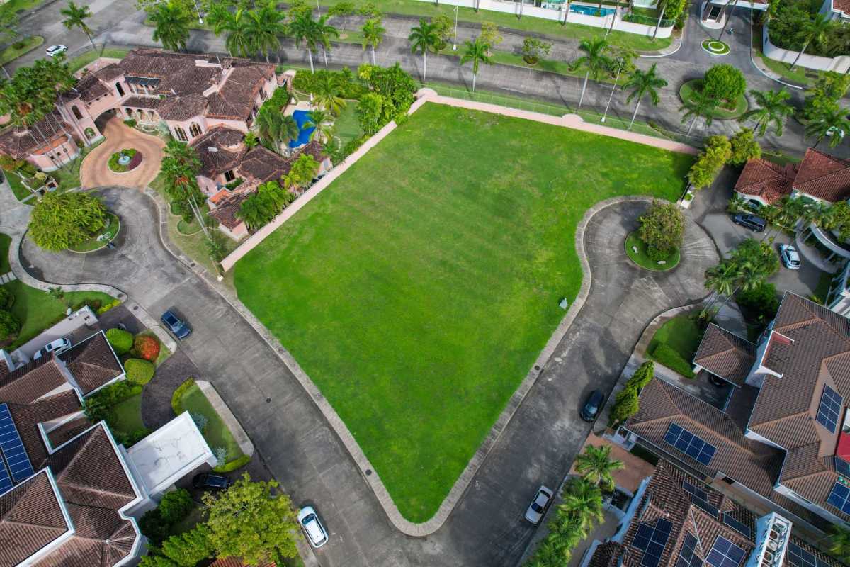 Large vacant green lot bordered by paved road and luxury homes Costa del Este Panama
