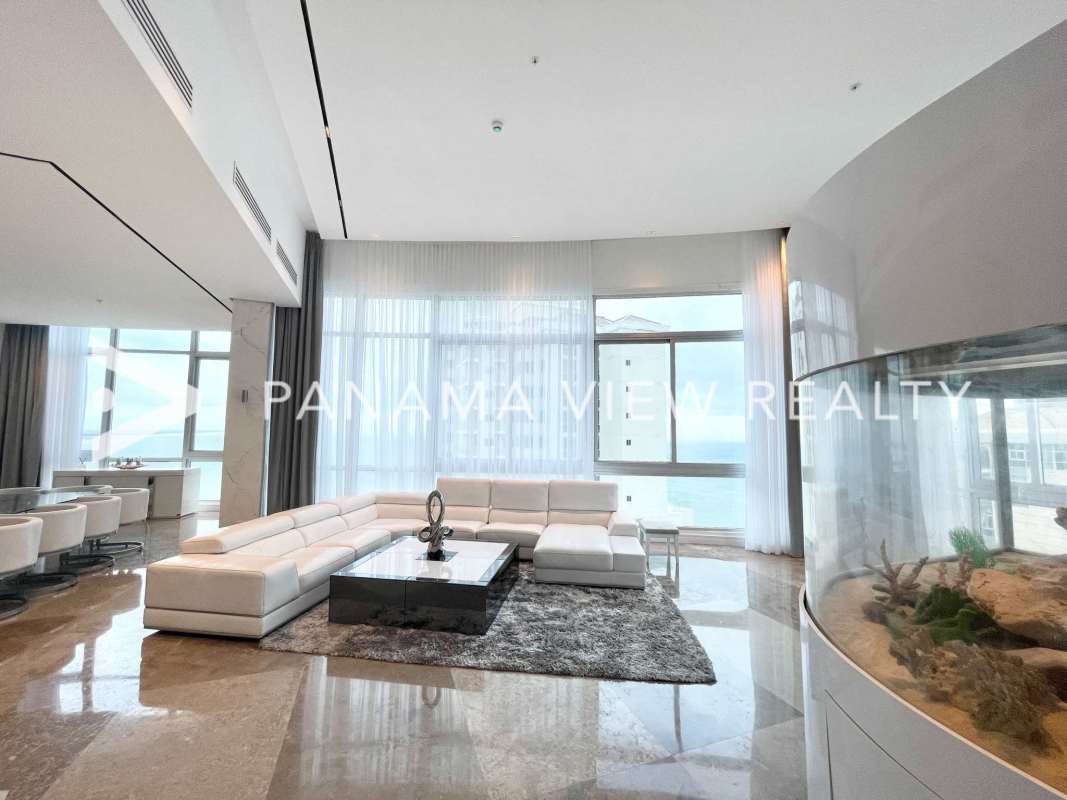 Modern living room with large windows, city and ocean views, and built-in aquarium in PH Blue Bahia Punta Pacifica