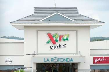 Shopping mall facade entrance with anchor supermarket Xtra and retail signage in Zona Libre Colón Panama