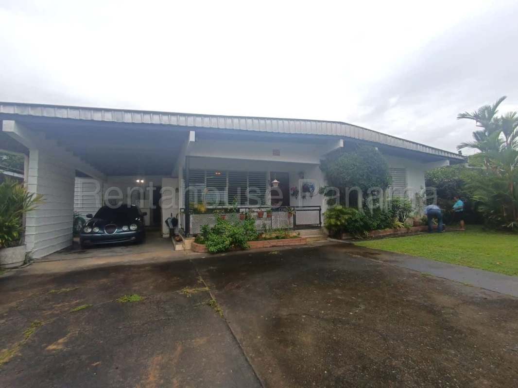 Exterior of single-story house with landscaped garden, gated parking and mature trees, located in San Francisco Panama