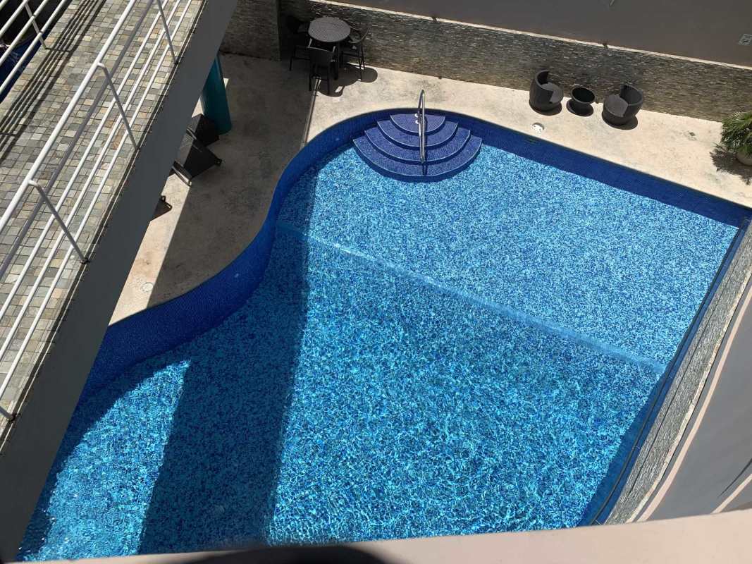 Aerial view of curved swimming pool with lounge chairs in PH Royal Princess Punta Paitilla