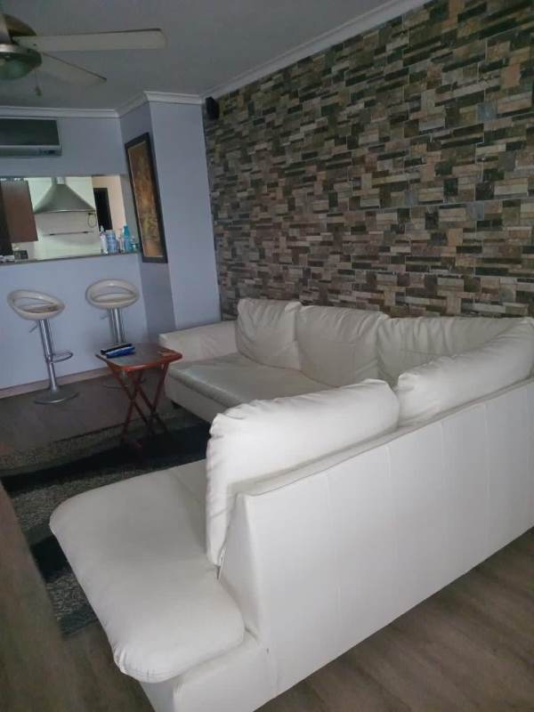 Living room with white sectional, accent wall, open kitchen in Dos Mares Tower Panama
