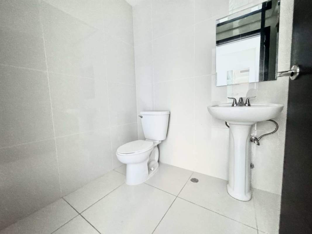 Minimalist bathroom with white tiles and pedestal sink inside commercial office space in Costa del Este Panama