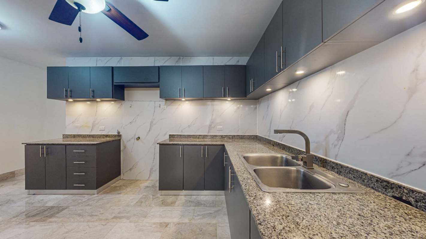 Modern kitchen with granite counters, dark cabinetry, marble-look backsplash in Sophia Tower Obarrio Panama