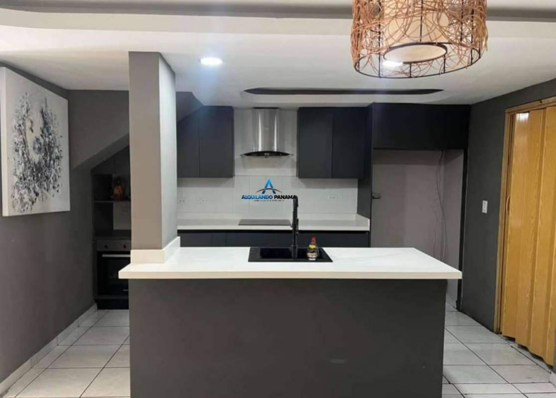 Open plan kitchen with gray cabinetry, central island, tile flooring house in Condado del Rey Panama for sale
