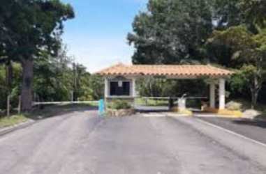 Gated entrance with Mediterranean guardhouse surrounded by trees at beach development Panama