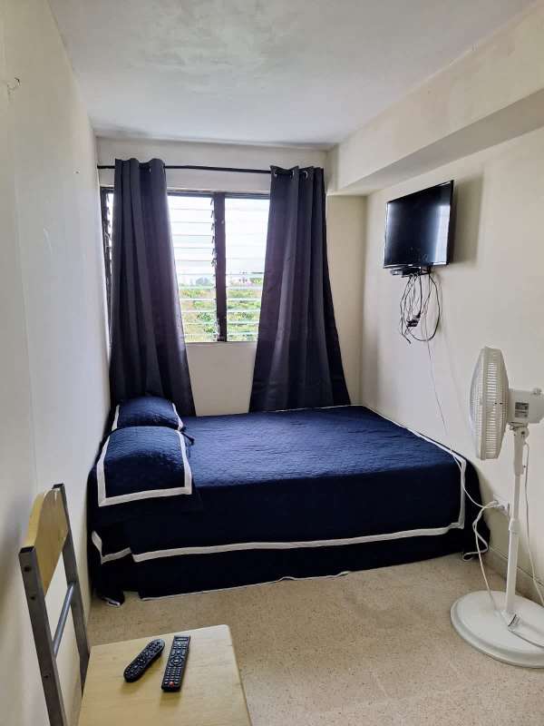 Small rental room with navy bedding, window with city view, wall TV El Carmen