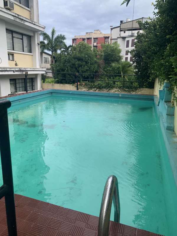 Outdoor pool beside mid-rise apartment building PH El Carmen 55 Panama