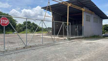 Secured fenced commercial yard area with gate, gravel lot and industrial buildings in La Chorrera Panama