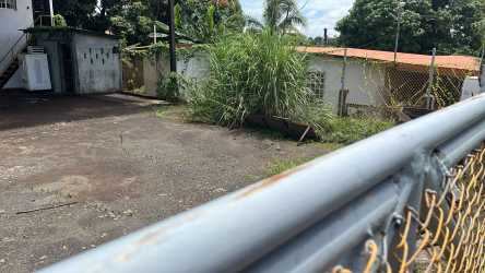 Side view of utilitarian metal-roofed warehouse with gravel yard in El Mastranto industrial area Panama