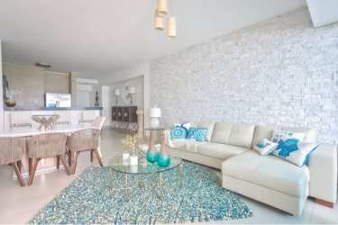 Contemporary oceanfront lounge area with teal sofas, pergola ceiling at Malibu Beach Residences Nueva Gorgona