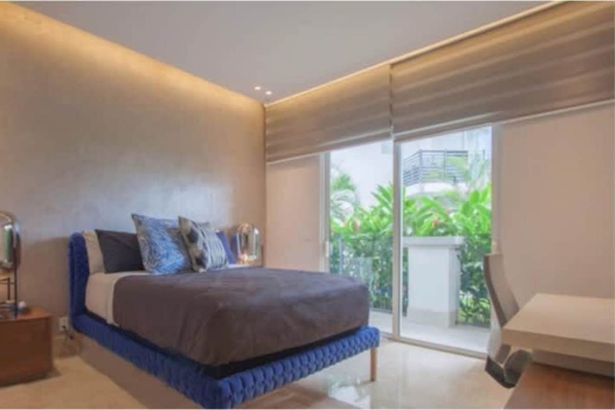 Luxury bedroom with sliding glass doors to balcony overlooking garden views and palm trees