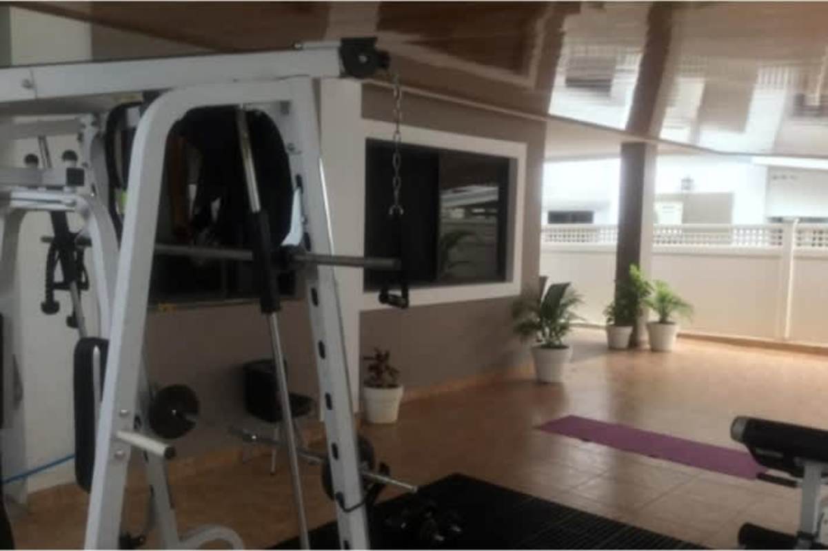 Modern dining area with glass-top table, accent wall, and sliding door to terrace in Panama City home