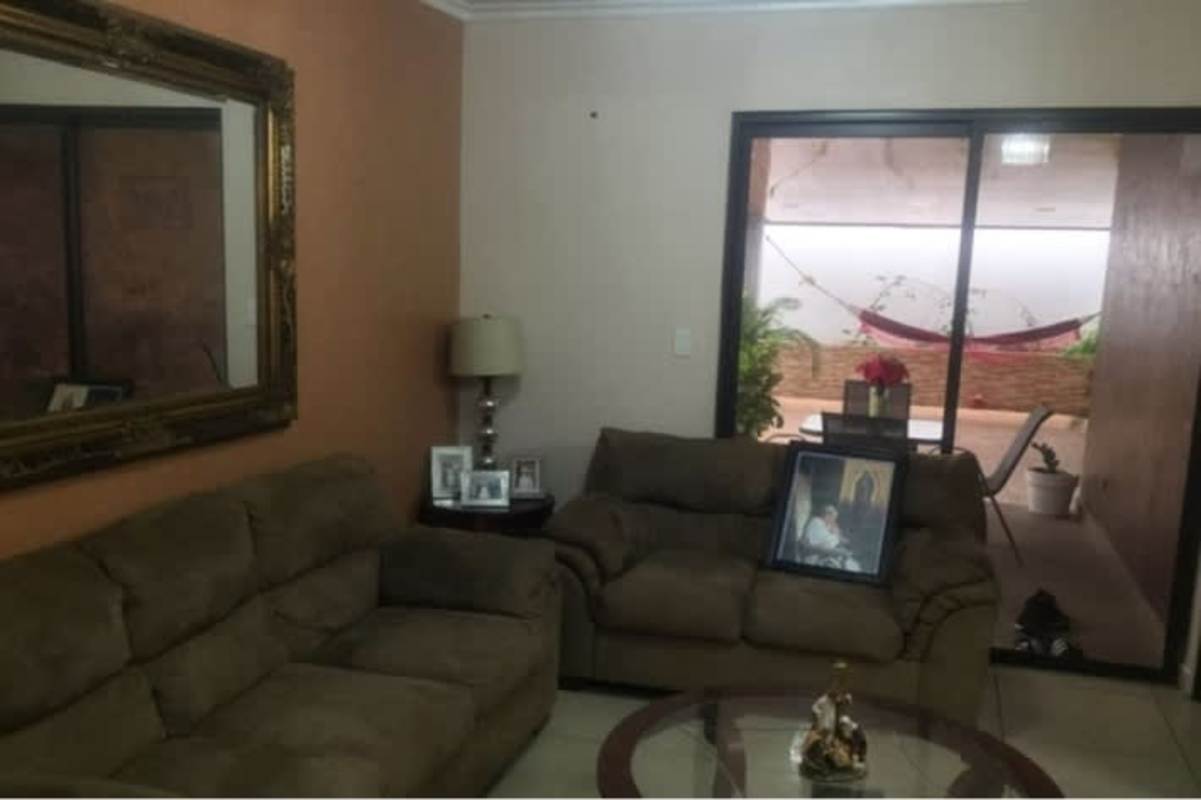 Bright living room with brown sofas, large mirror and sliding doors overlooking patio in Panama home