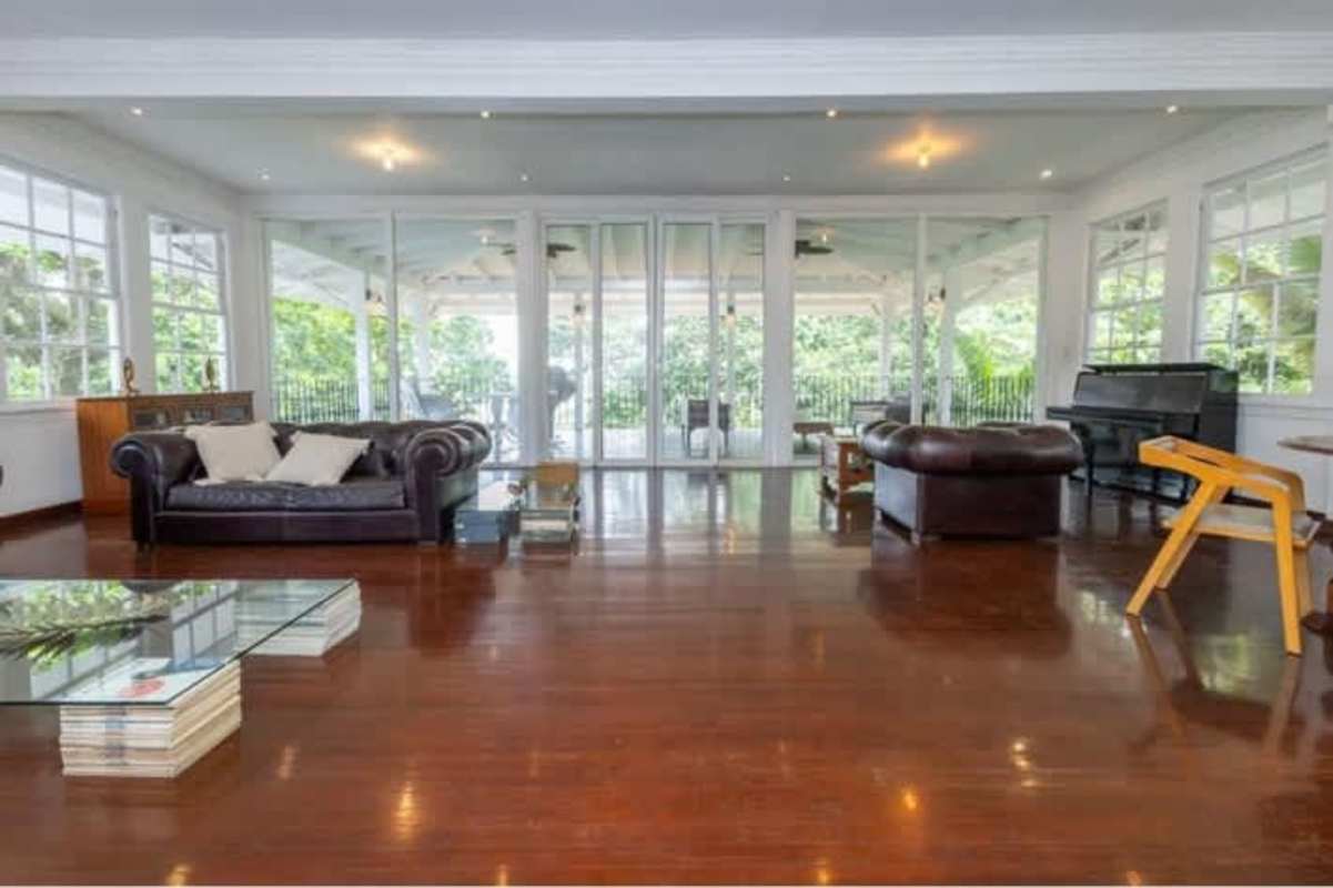 Spacious living room with hardwood floors, leather sofas, garden views and natural light in Casa Gorgas Panama