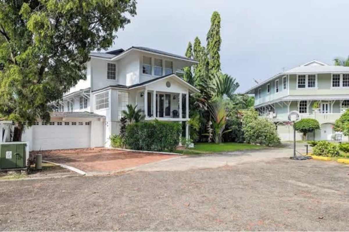 Colonial-style veranda with seating and ceiling fans overlooking lush garden at Casa Gorgas, Ancón Panama