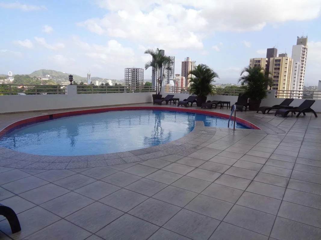 Rooftop infinity swimming pool overlooking city skyline with lounge chairs in PH Hato Pintado