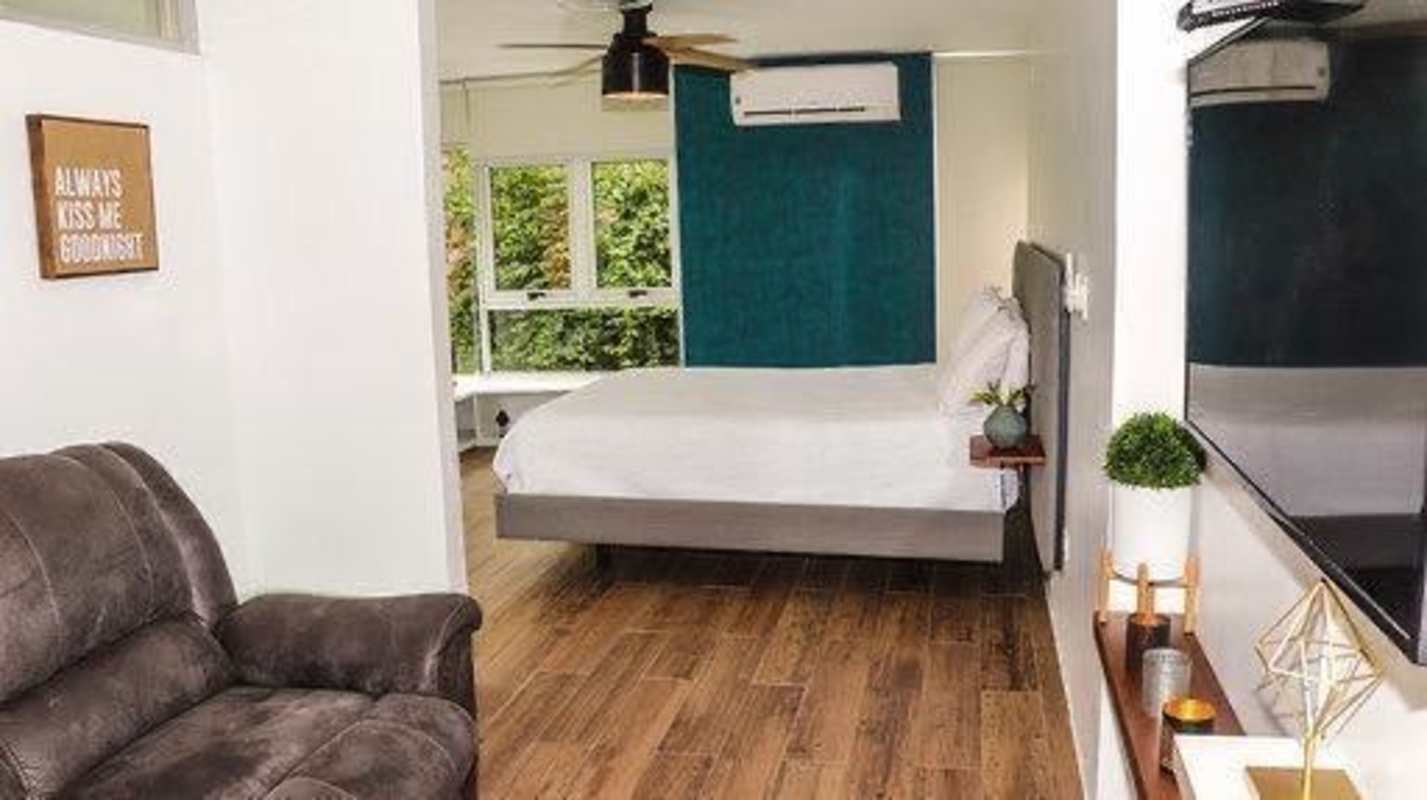 Bedroom with large windows overlooking garden, wood floors in Condado del Rey house Panama